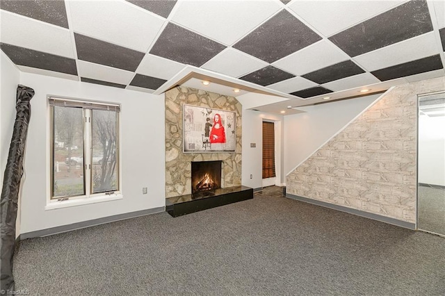 unfurnished living room with stairway, baseboards, a fireplace, carpet flooring, and a wealth of natural light