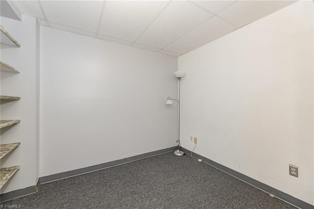 unfurnished room featuring a paneled ceiling, baseboards, and dark carpet