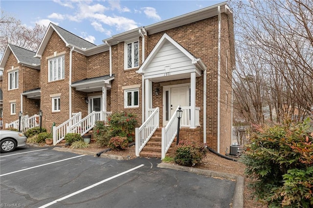 multi unit property featuring brick siding, central AC, and uncovered parking