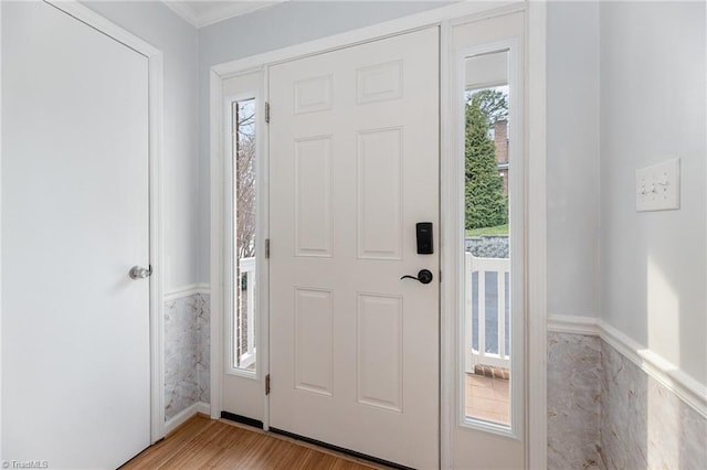 entryway with light wood-style floors and ornamental molding