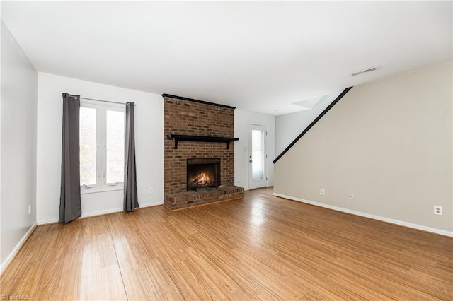 unfurnished living room with light wood-type flooring, baseboards, visible vents, and a fireplace