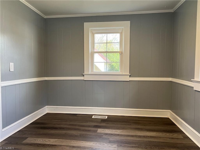 spare room with crown molding, wooden walls, and dark hardwood / wood-style flooring