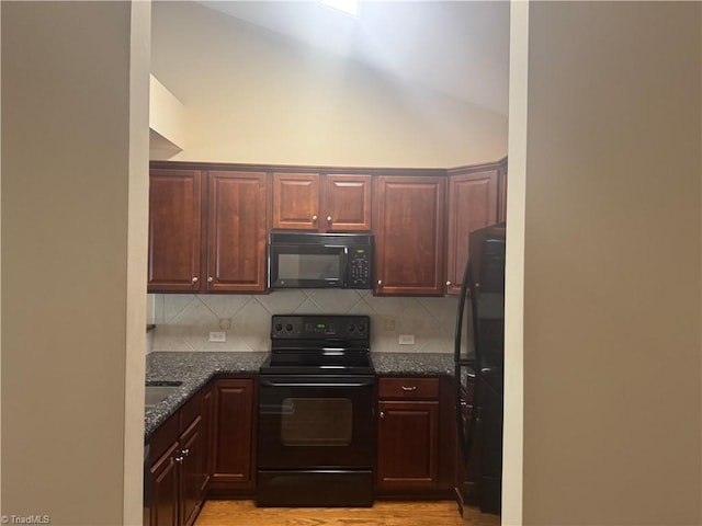 401 Pelican Ln, Clemmons, NC 27012 - kitchen featuring dark stone counters, vaulted ceiling, black appliances, light wood finished floors, and backsplash