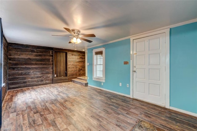 interior space featuring wood walls, crown molding, ceiling fan, and hardwood / wood-style floors