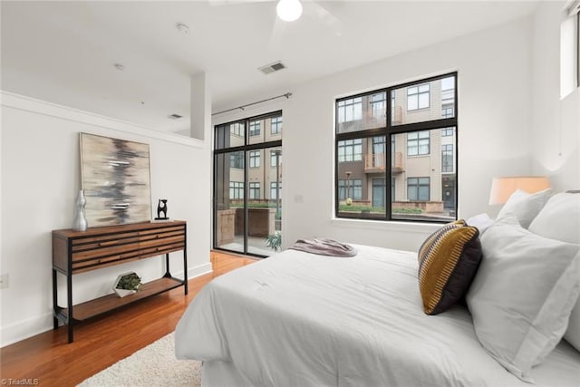 bedroom with ceiling fan, wood-type flooring, and access to outside