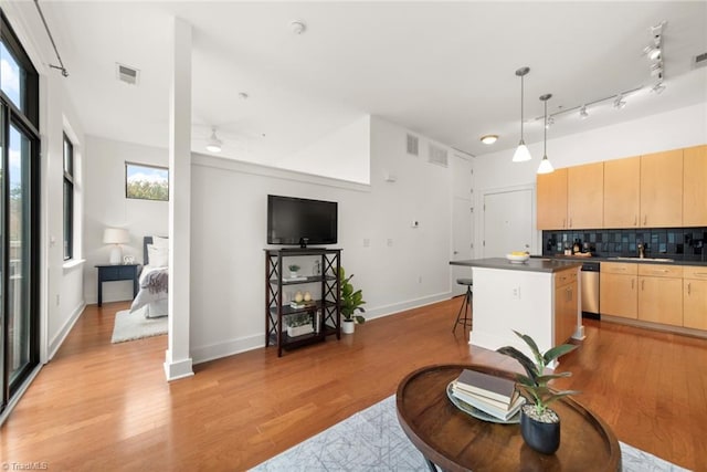 kitchen with plenty of natural light, light brown cabinetry, tasteful backsplash, and light hardwood / wood-style flooring