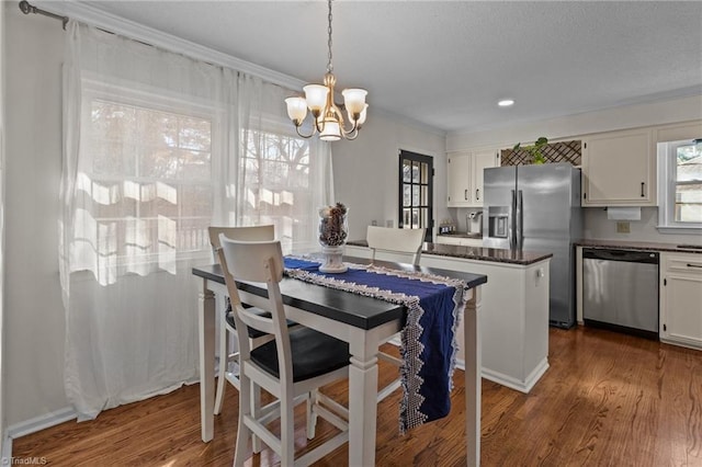 dining area featuring dark wood-type flooring, crown molding, and an inviting chandelier