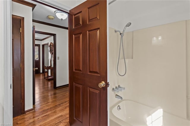 bathroom with hardwood / wood-style floors, ornamental molding, and bathtub / shower combination