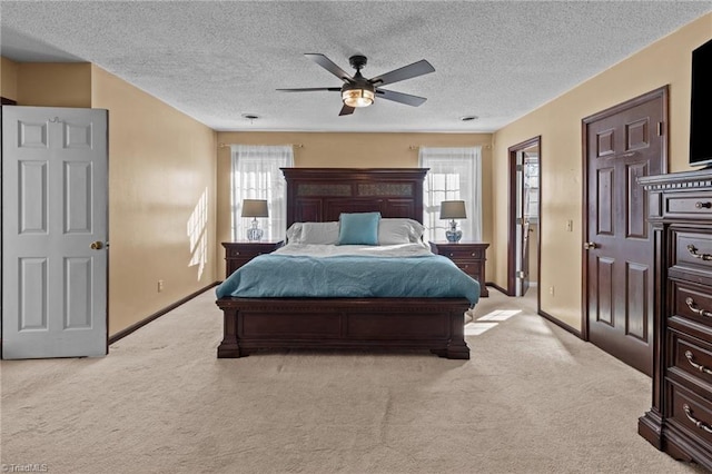 bedroom featuring multiple windows, a textured ceiling, light carpet, and ceiling fan