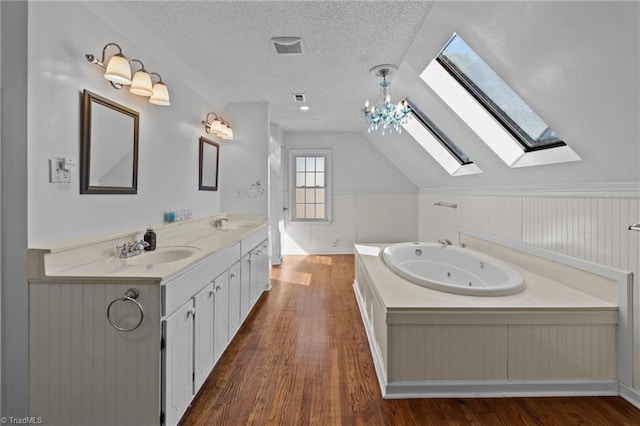 bathroom featuring lofted ceiling, a textured ceiling, vanity, a bathing tub, and hardwood / wood-style flooring