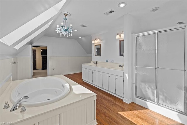 bathroom featuring vanity, vaulted ceiling with skylight, hardwood / wood-style floors, and shower with separate bathtub