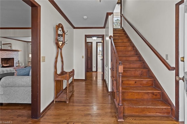 stairway with hardwood / wood-style flooring, crown molding, and a fireplace