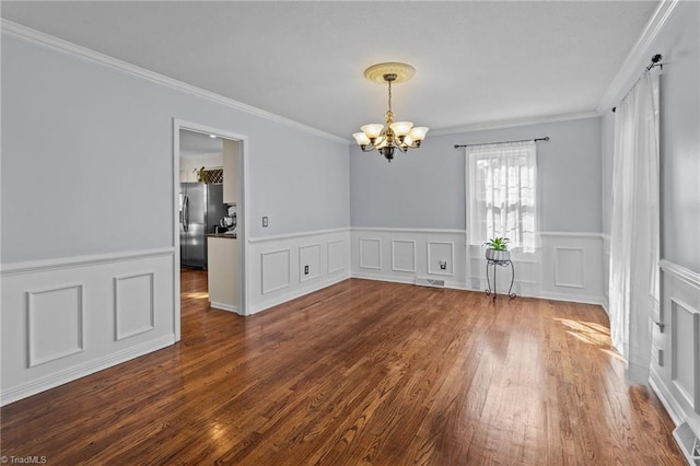 empty room with crown molding, dark hardwood / wood-style floors, and an inviting chandelier