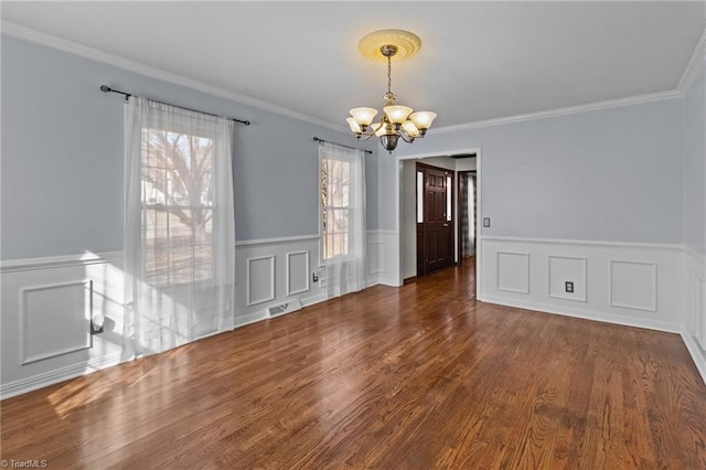 unfurnished dining area featuring an inviting chandelier, crown molding, and dark wood-type flooring