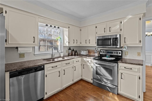 kitchen featuring sink, white cabinetry, stainless steel appliances, dark hardwood / wood-style flooring, and dark stone counters