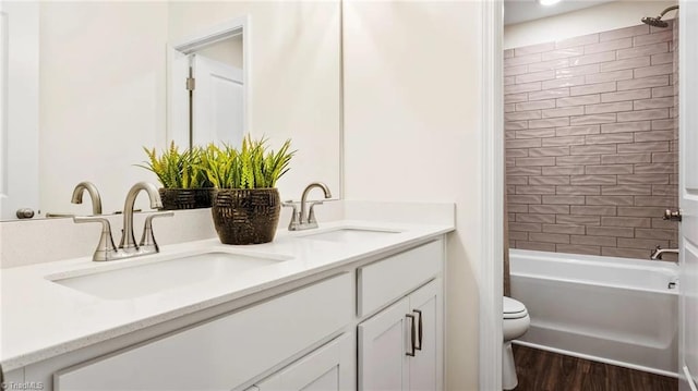 full bathroom featuring hardwood / wood-style flooring, tiled shower / bath combo, toilet, and vanity