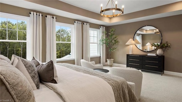 carpeted bedroom featuring a raised ceiling and an inviting chandelier