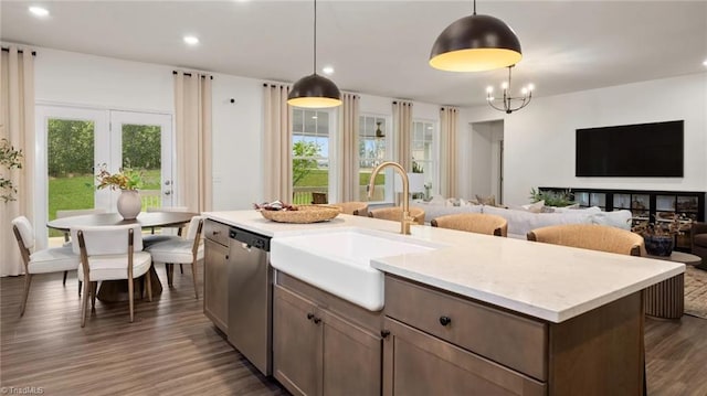 kitchen featuring sink, an inviting chandelier, stainless steel dishwasher, decorative light fixtures, and a kitchen island with sink