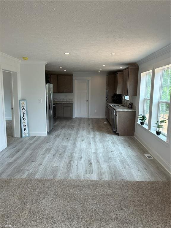 kitchen featuring a textured ceiling, light hardwood / wood-style floors, stainless steel fridge with ice dispenser, and ornamental molding