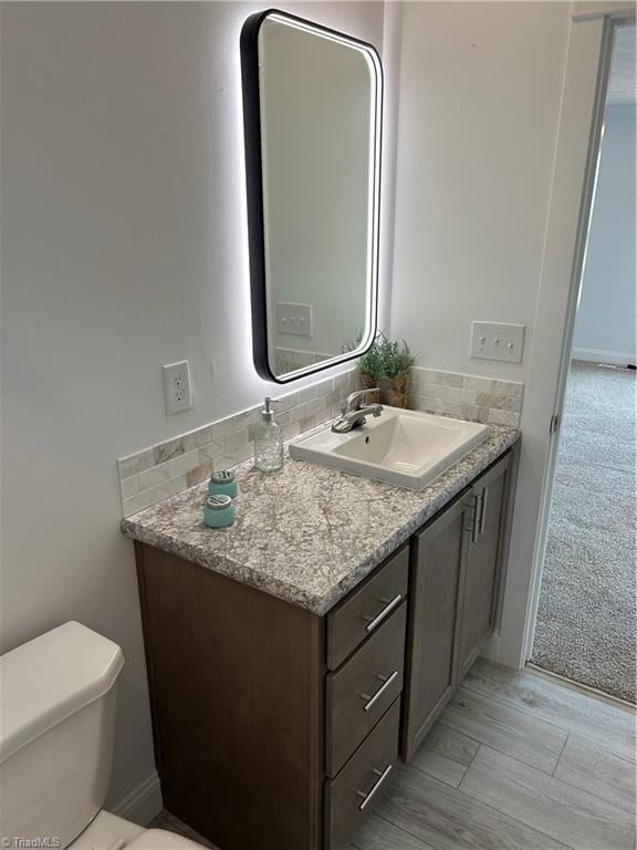 bathroom with vanity, toilet, decorative backsplash, and wood-type flooring