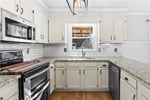 kitchen featuring stainless steel appliances, light stone countertops, decorative backsplash, sink, and white cabinetry