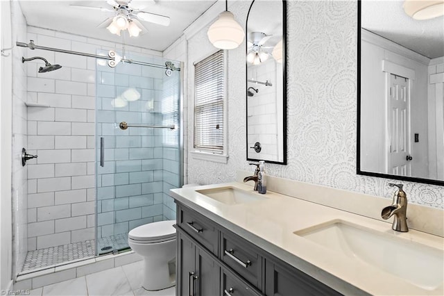 bathroom with a stall shower, a sink, toilet, and wallpapered walls