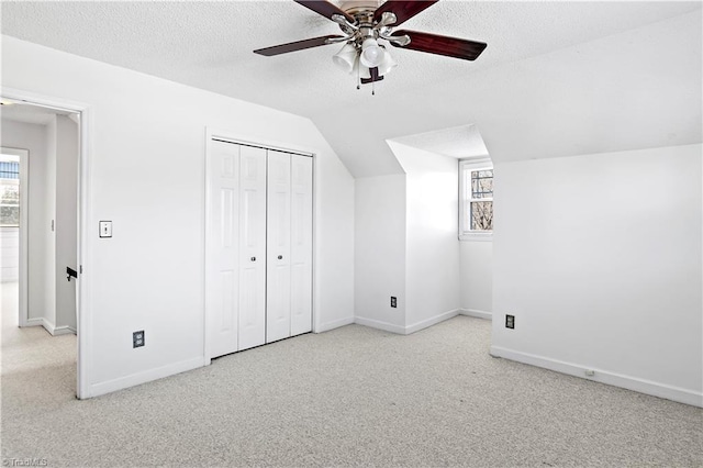 additional living space featuring baseboards, lofted ceiling, ceiling fan, a textured ceiling, and carpet floors