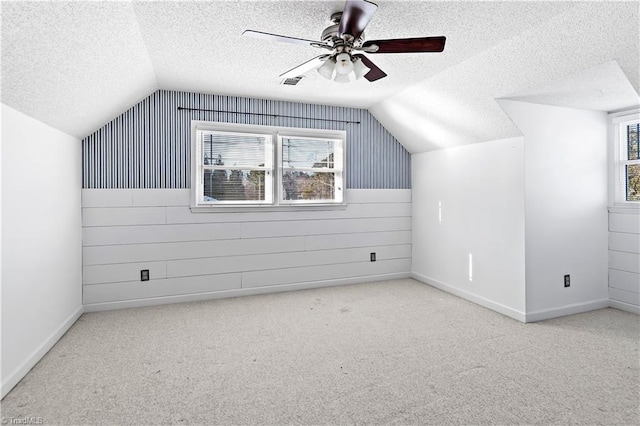 additional living space featuring vaulted ceiling, ceiling fan, a textured ceiling, and carpet flooring