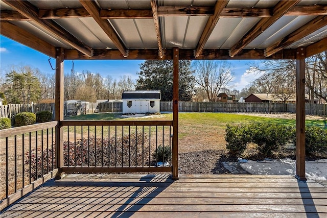 deck featuring an outbuilding, a fenced backyard, a grill, a yard, and a storage unit