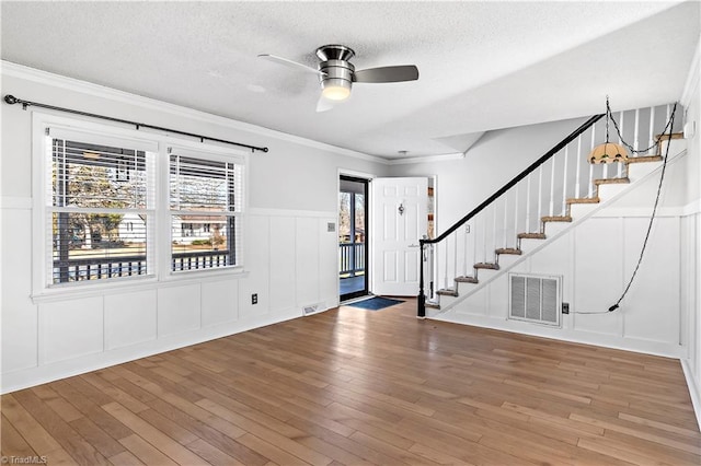 entryway with a textured ceiling, ceiling fan, ornamental molding, and hardwood / wood-style floors