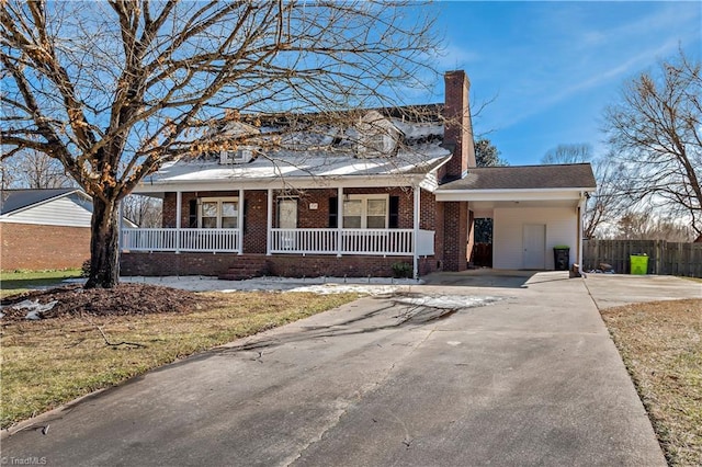 view of front of home featuring driveway, a chimney, covered porch, fence, and brick siding