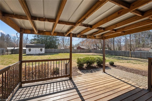 deck featuring a patio area, a lawn, an outdoor structure, and a fenced backyard