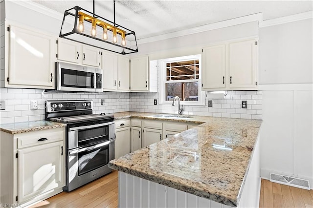 kitchen with sink, white cabinetry, pendant lighting, and appliances with stainless steel finishes