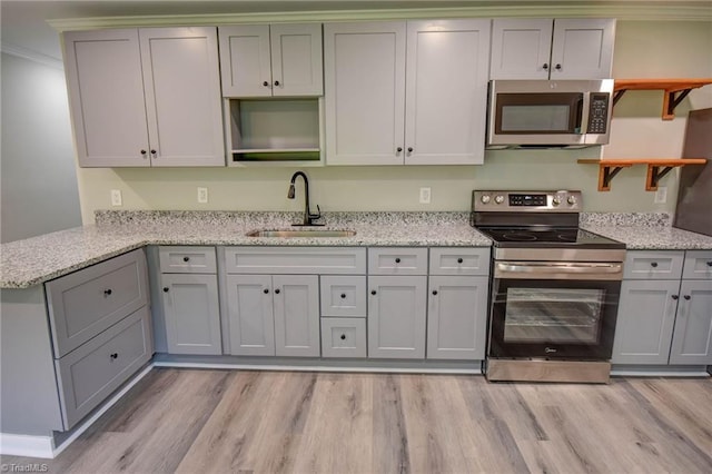 714 Martin St, Greensboro, NC 27406 - kitchen with open shelves, a sink, light stone counters, light wood finished floors, and stainless steel appliances