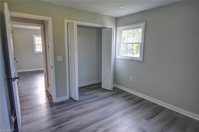 714 Martin St, Greensboro, NC 27406 - unfurnished bedroom with baseboards, multiple windows, and wood finished floors