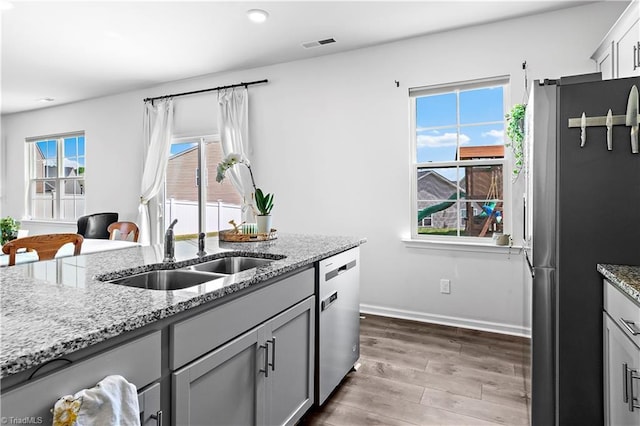 kitchen with a sink, wood finished floors, a wealth of natural light, and stainless steel appliances