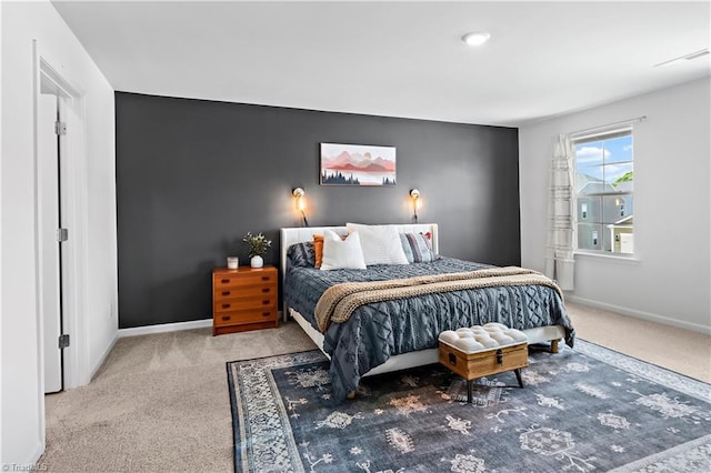 carpeted bedroom featuring baseboards, an accent wall, and visible vents
