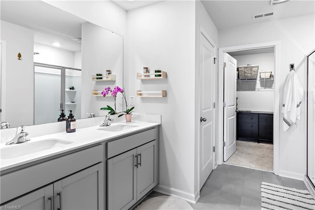 bathroom with baseboards, visible vents, a sink, and a stall shower