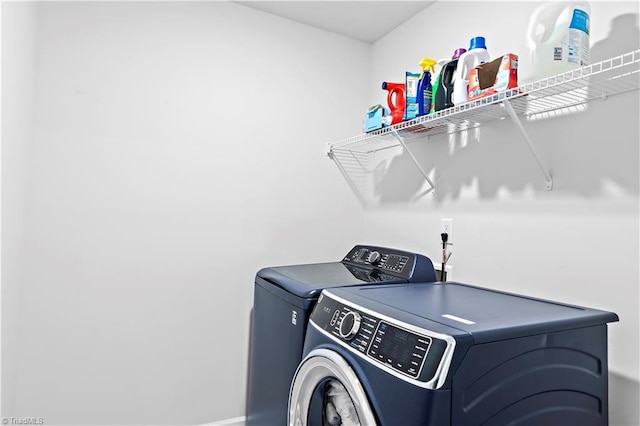washroom with baseboards, laundry area, and washing machine and clothes dryer