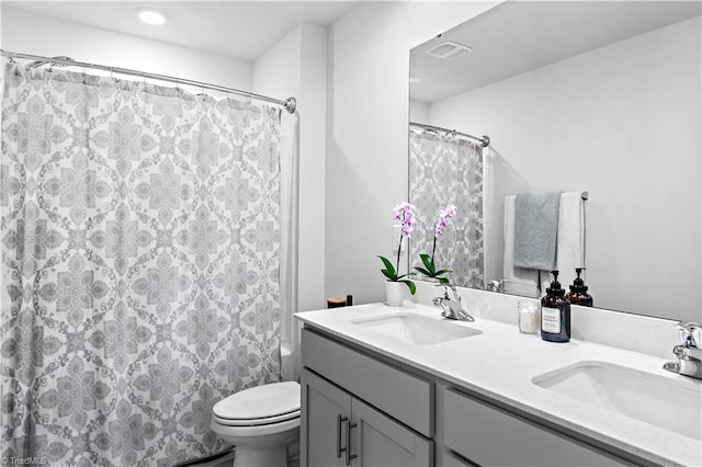 full bathroom featuring double vanity, a sink, visible vents, and toilet