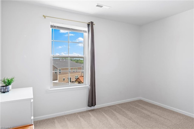 carpeted spare room featuring baseboards and visible vents