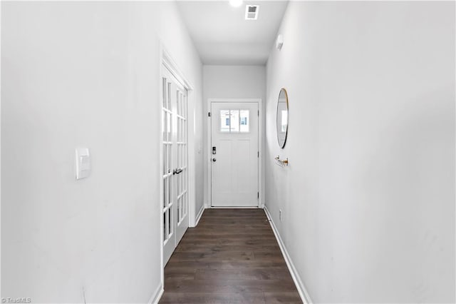 doorway with dark wood-type flooring, baseboards, and visible vents