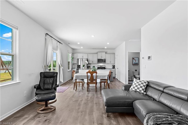 living area featuring recessed lighting, baseboards, and light wood finished floors