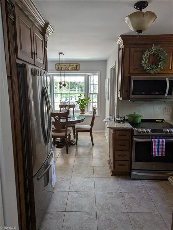 kitchen with decorative light fixtures, a notable chandelier, appliances with stainless steel finishes, and light tile patterned floors