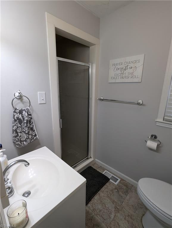 bathroom featuring vanity, a shower with shower door, and toilet