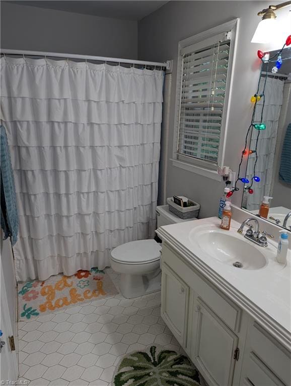 bathroom with tile patterned floors, a shower with curtain, vanity, and toilet