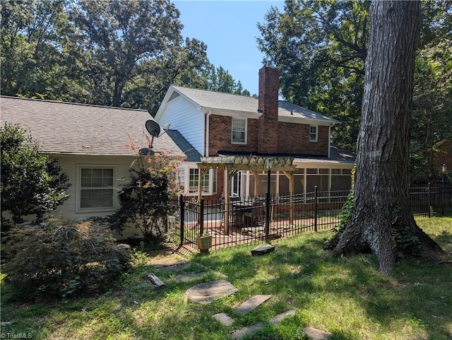 rear view of house featuring a pergola and a yard