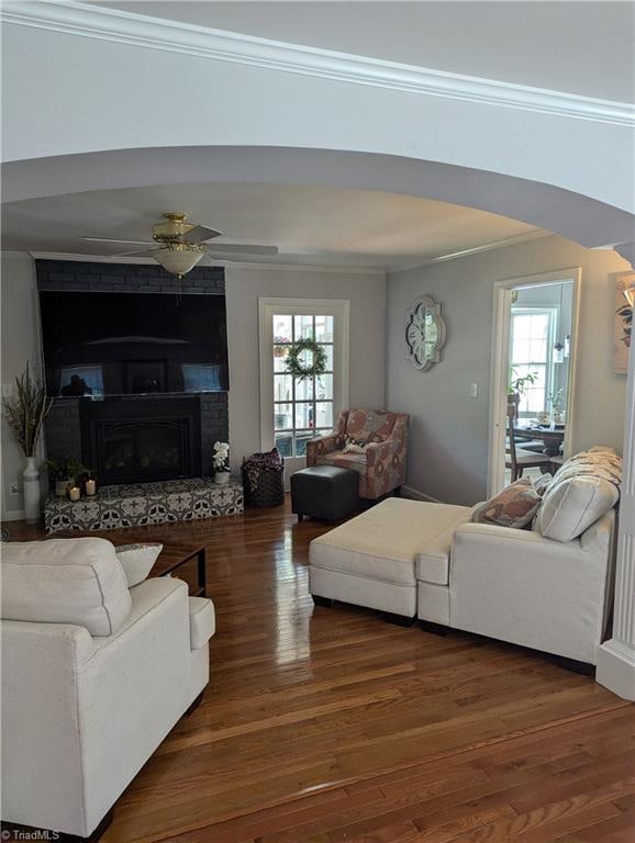 living room featuring a healthy amount of sunlight, dark hardwood / wood-style floors, and a brick fireplace