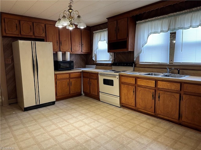 kitchen with sink, a chandelier, decorative light fixtures, white appliances, and wooden walls