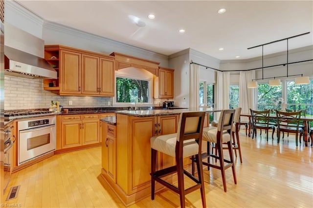 10 Sunfish Pt, Greensboro, NC 27455 - kitchen featuring appliances with stainless steel finishes, crown molding, light wood-type flooring, a kitchen bar, and tasteful backsplash